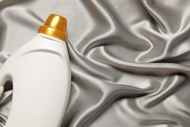 Photo of Bottle of fabric softener on grey cloth, top view. Space for text