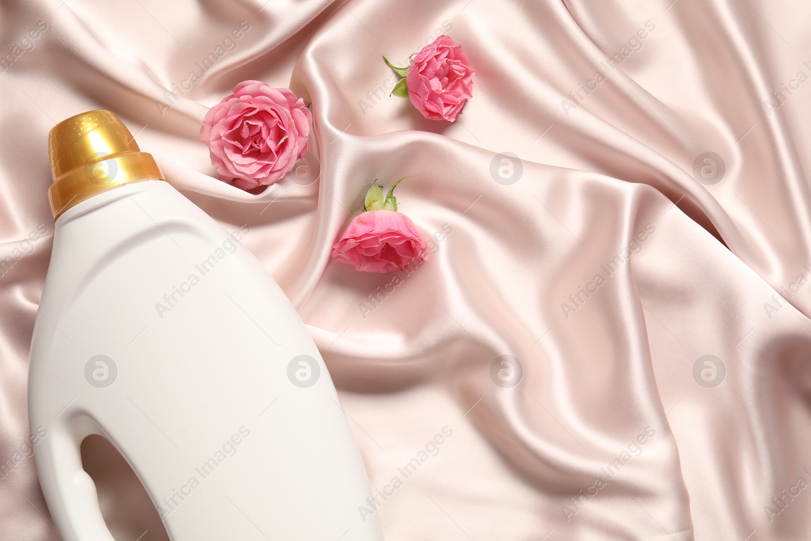 Bottle of fabric softener and flowers on beige cloth, flat lay. Space for text Photo of Bottle of fabric softener and flowers on beige cloth, flat lay. Space for text