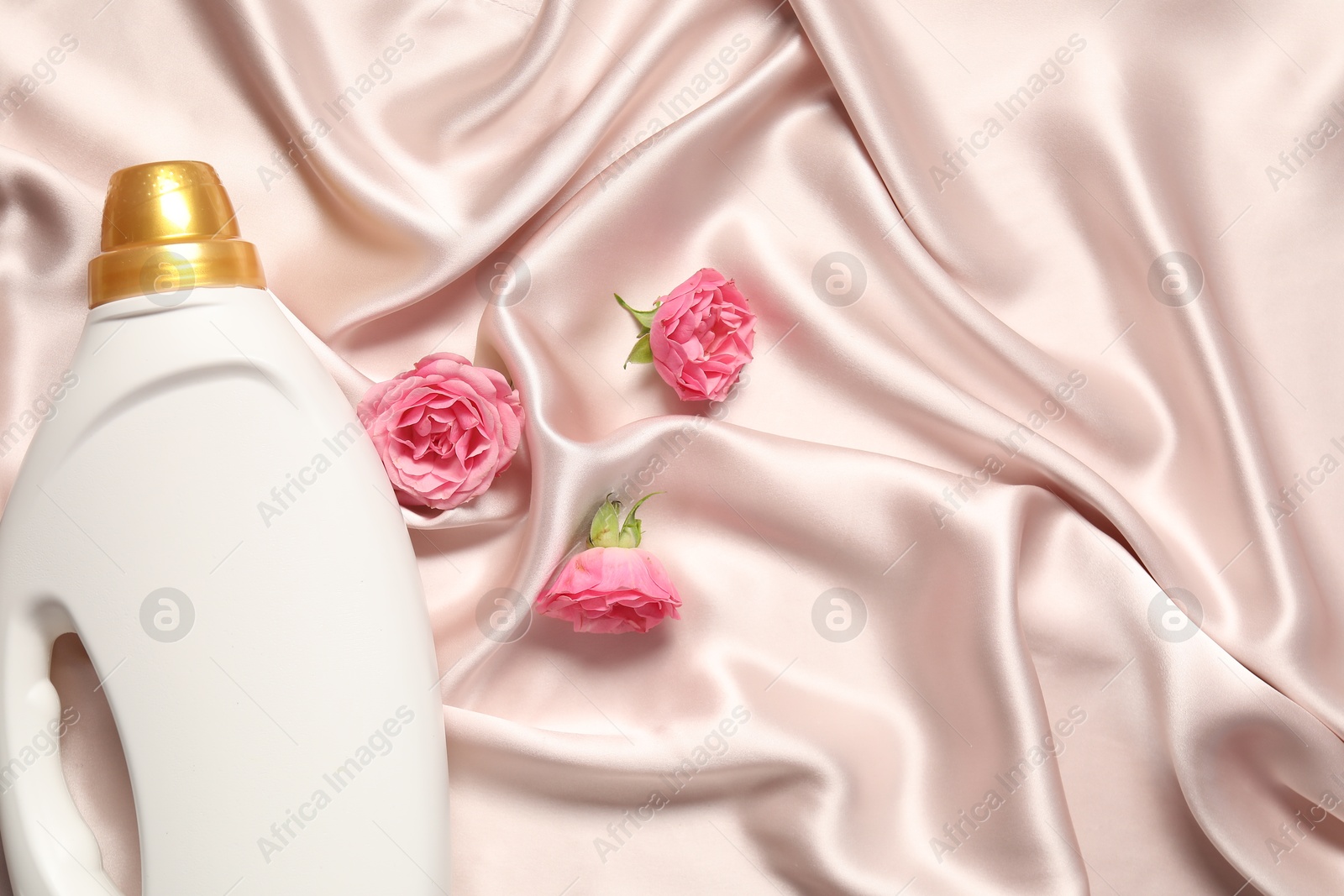 Bottle of fabric softener and flowers on beige cloth, flat lay. Space for text Photo of Bottle of fabric softener and flowers on beige cloth, flat lay. Space for text