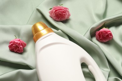 Photo of Bottle of fabric softener and flowers on green cloth, above view