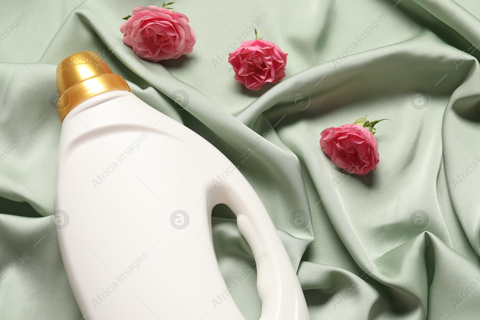 Bottle of fabric softener and flowers on green cloth, above view Photo of Bottle of fabric softener and flowers on green cloth, above view