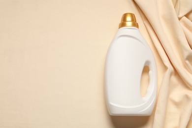 Photo of Bottle of fabric softener on beige background, top view. Space for text