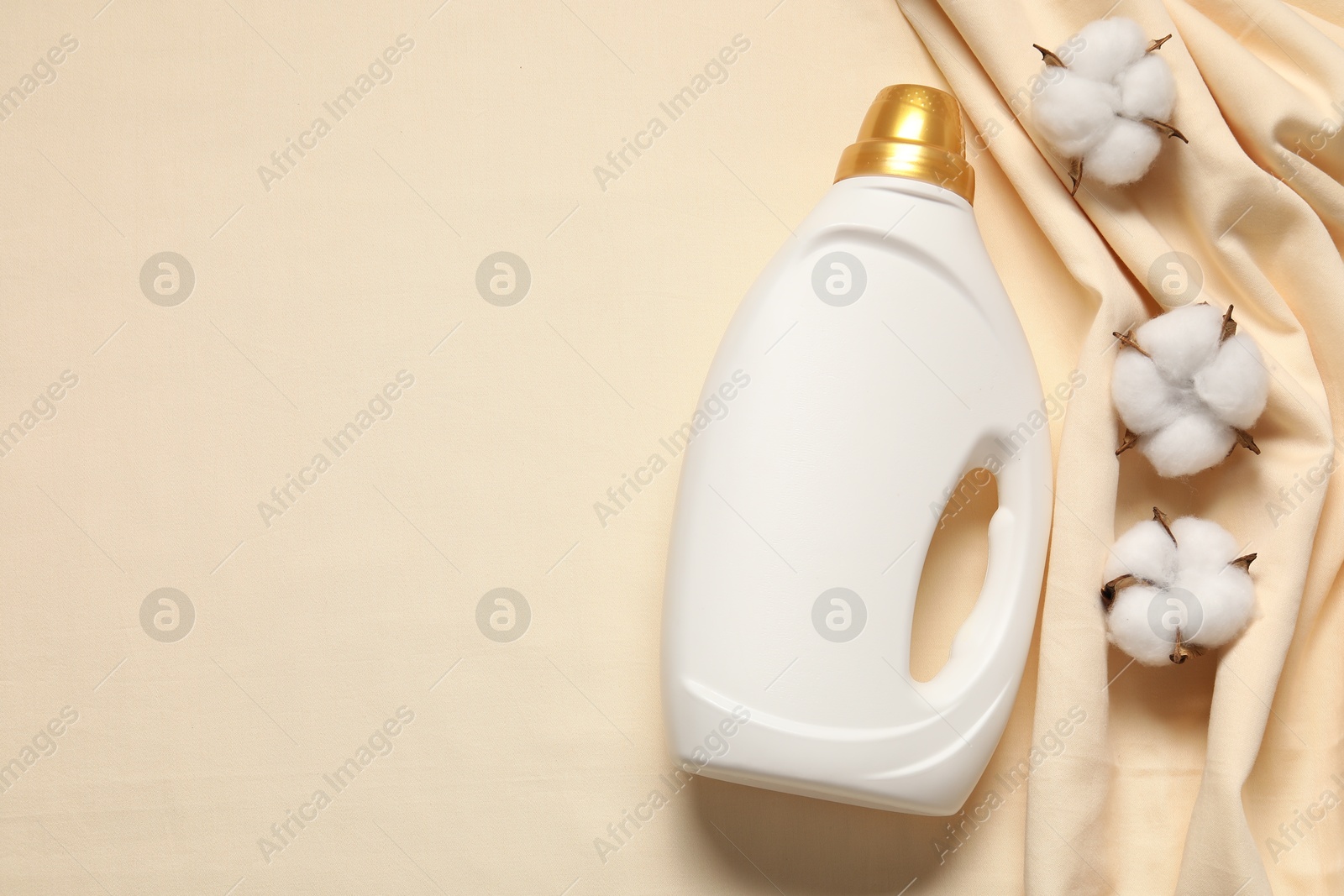 Bottle of fabric softener and cotton flowers on beige background, flat lay. Space for text Photo of Bottle of fabric softener and cotton flowers on beige background, flat lay. Space for text