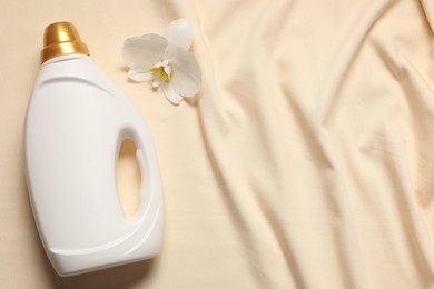 Photo of Bottle of fabric softener and orchid flower on beige background, flat lay. Space for text