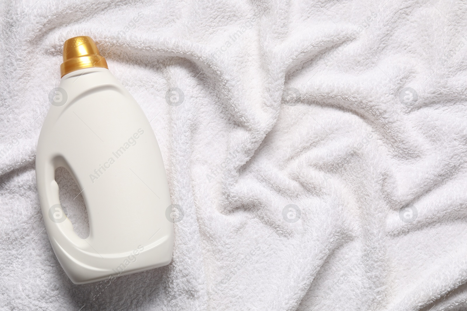 Bottle of fabric softener on terry towel, top view. Space for text Photo of Bottle of fabric softener on terry towel, top view. Space for text