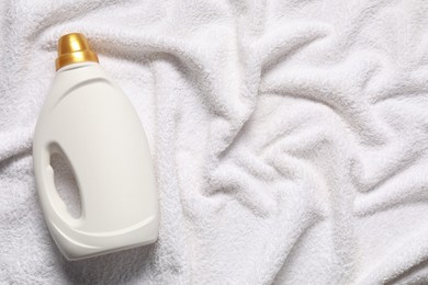 Photo of Bottle of fabric softener on terry towel, top view. Space for text