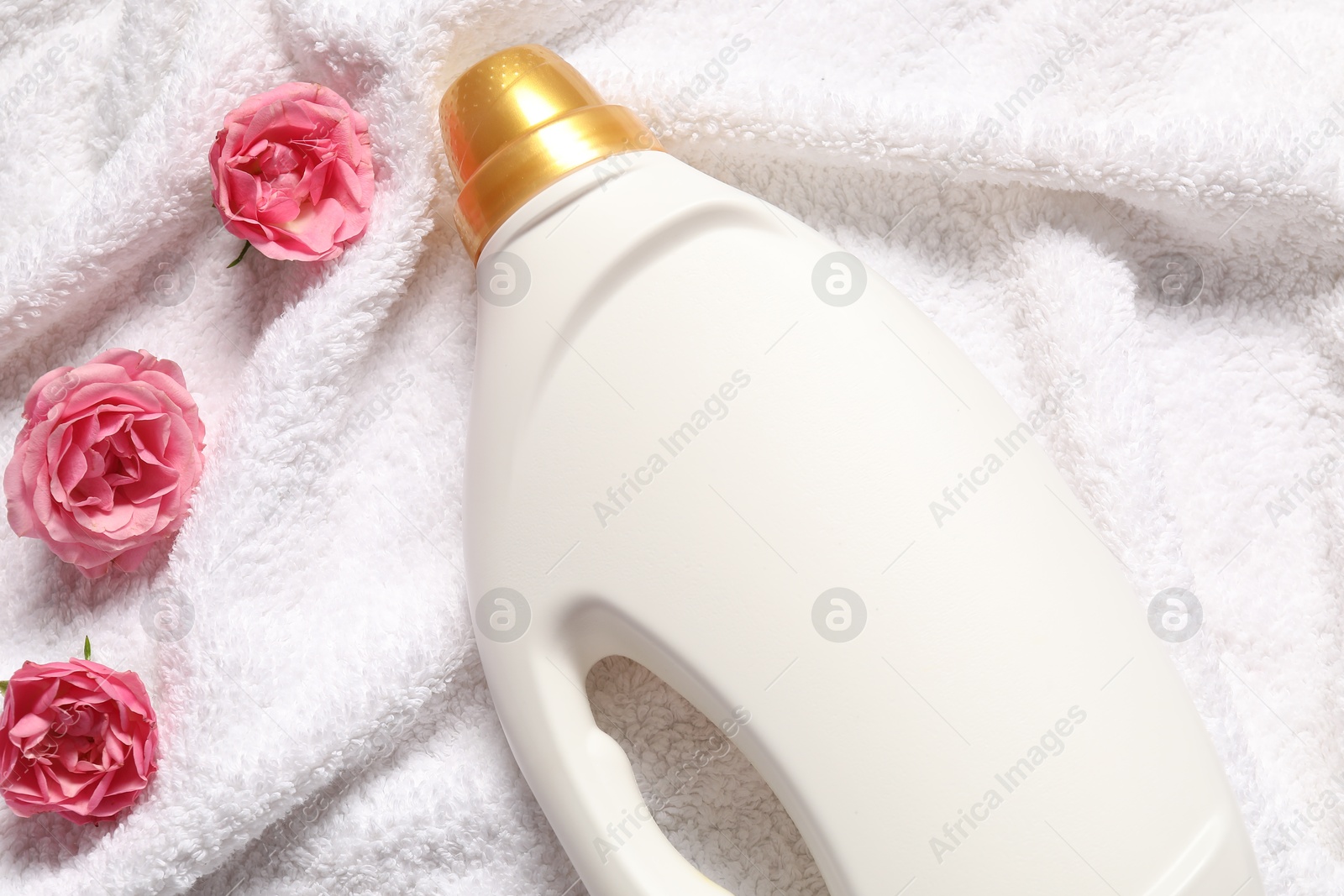Bottle of fabric softener and flowers on terry towel, above view Photo of Bottle of fabric softener and flowers on terry towel, above view