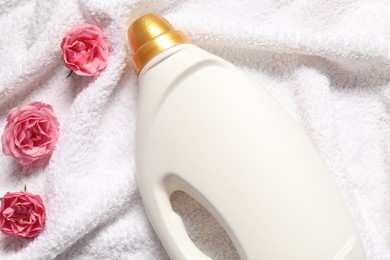 Photo of Bottle of fabric softener and flowers on terry towel, above view