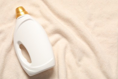 Photo of Bottle of fabric softener on soft cloth, top view. Space for text