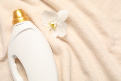 Photo of Bottle of fabric softener and orchid flower on soft cloth, flat lay. Space for text