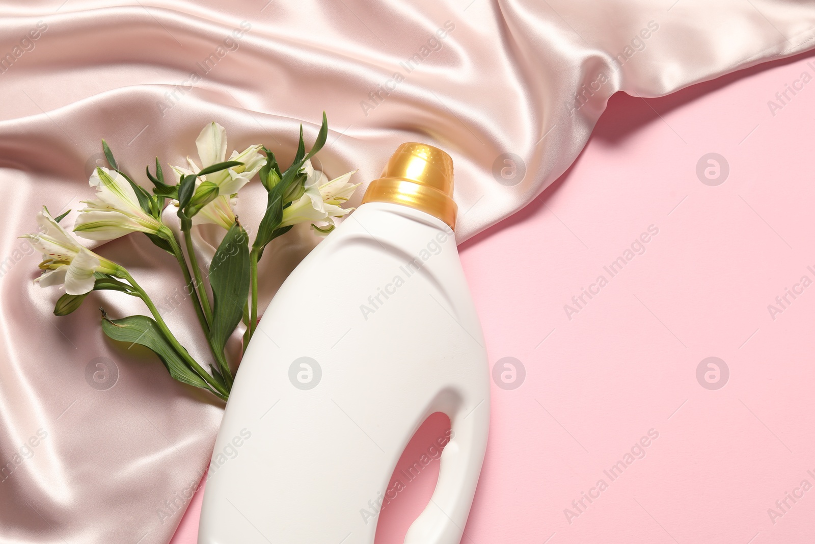 Bottle of fabric softener, flowers and beige cloth on pink background, flat lay. Space for text Photo of Bottle of fabric softener, flowers and beige cloth on pink background, flat lay. Space for text