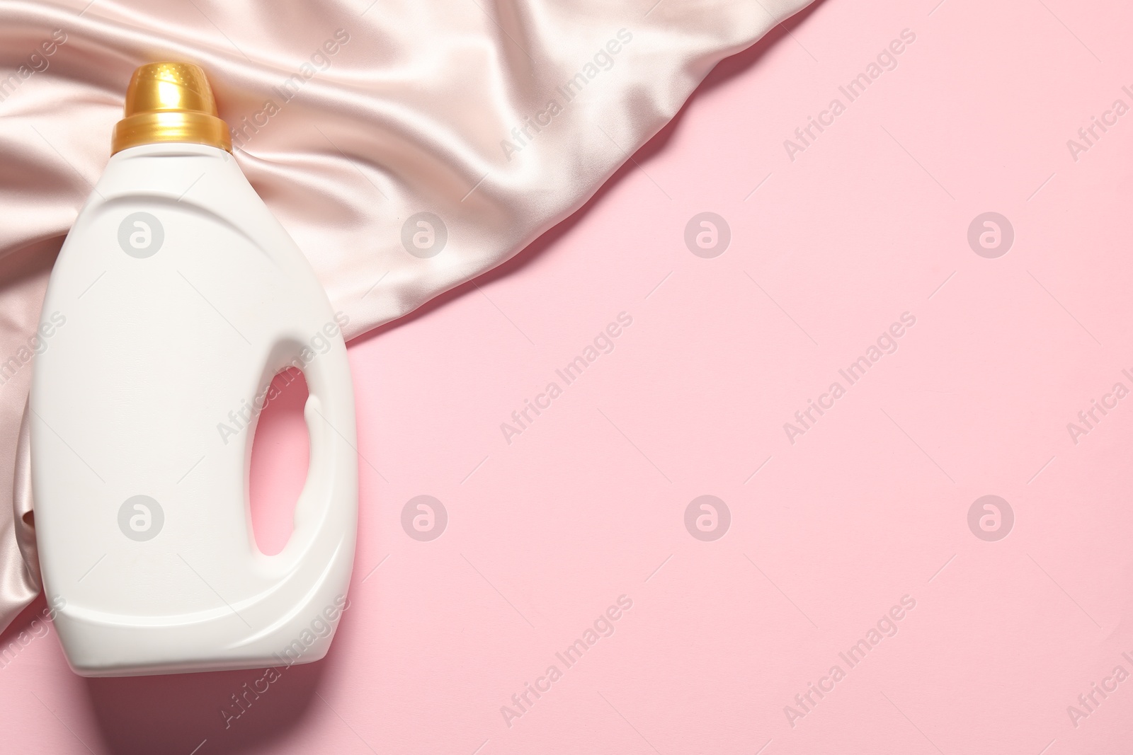 Bottle of fabric softener and beige cloth on pink background, top view. Space for text Photo of Bottle of fabric softener and beige cloth on pink background, top view. Space for text