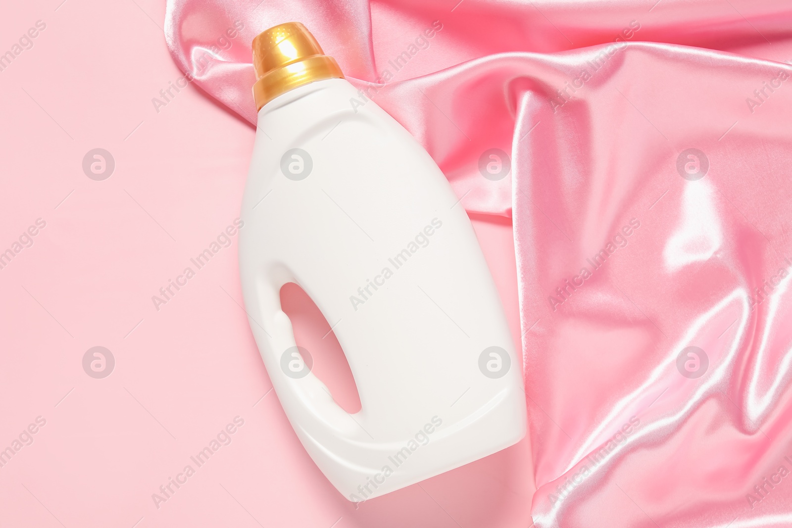 Bottle of fabric softener and color cloth on pink background, top view Photo of Bottle of fabric softener and color cloth on pink background, top view