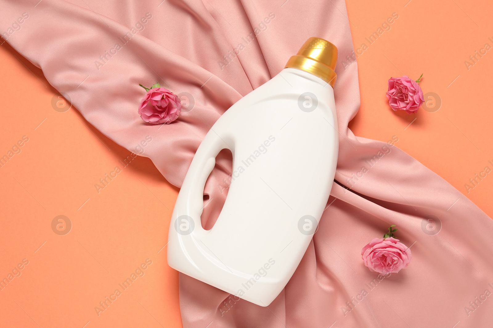 Bottle of fabric softener, flowers and pink cloth on coral background, flat lay Photo of Bottle of fabric softener, flowers and pink cloth on coral background, flat lay