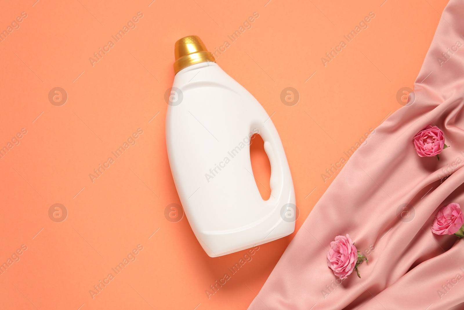Bottle of fabric softener, flowers and pink cloth on coral background, flat lay Photo of Bottle of fabric softener, flowers and pink cloth on coral background, flat lay