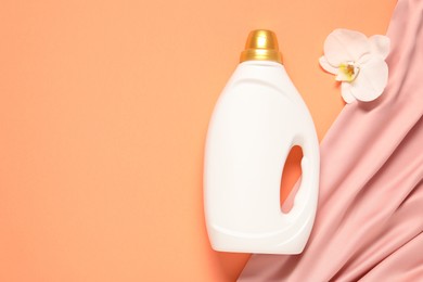 Photo of Bottle of fabric softener, orchid flower and pink cloth on coral background, flat lay. Space for text