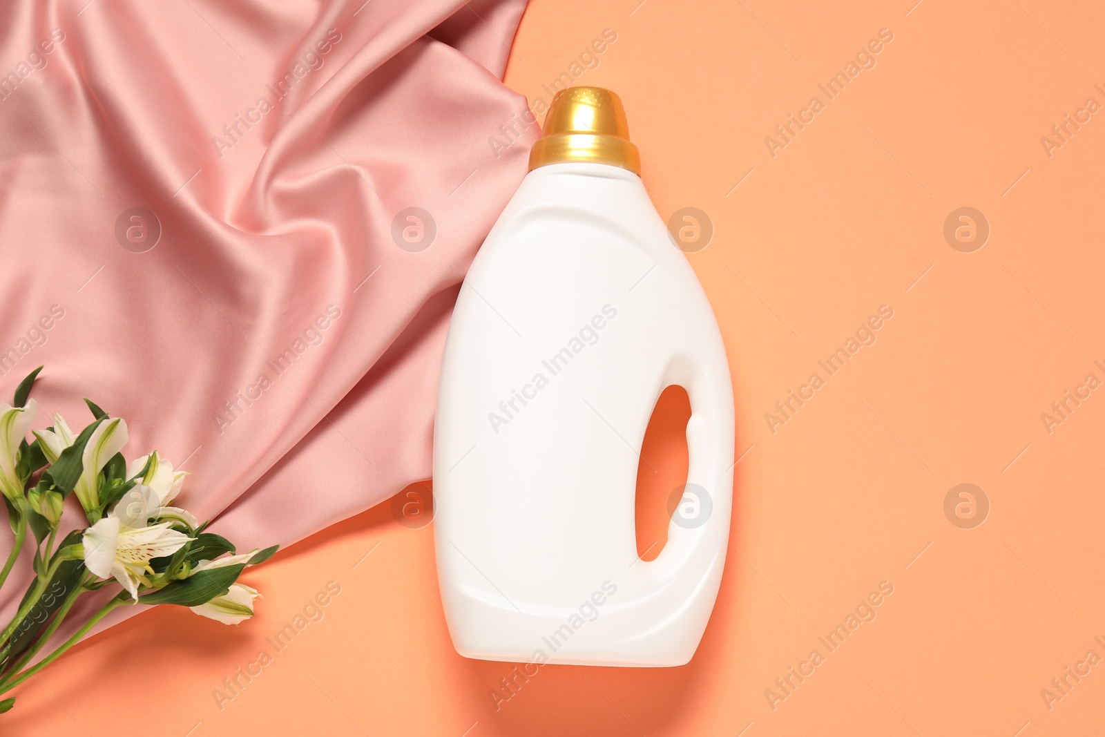 Bottle of fabric softener, flowers and pink cloth on coral background, flat lay Photo of Bottle of fabric softener, flowers and pink cloth on coral background, flat lay