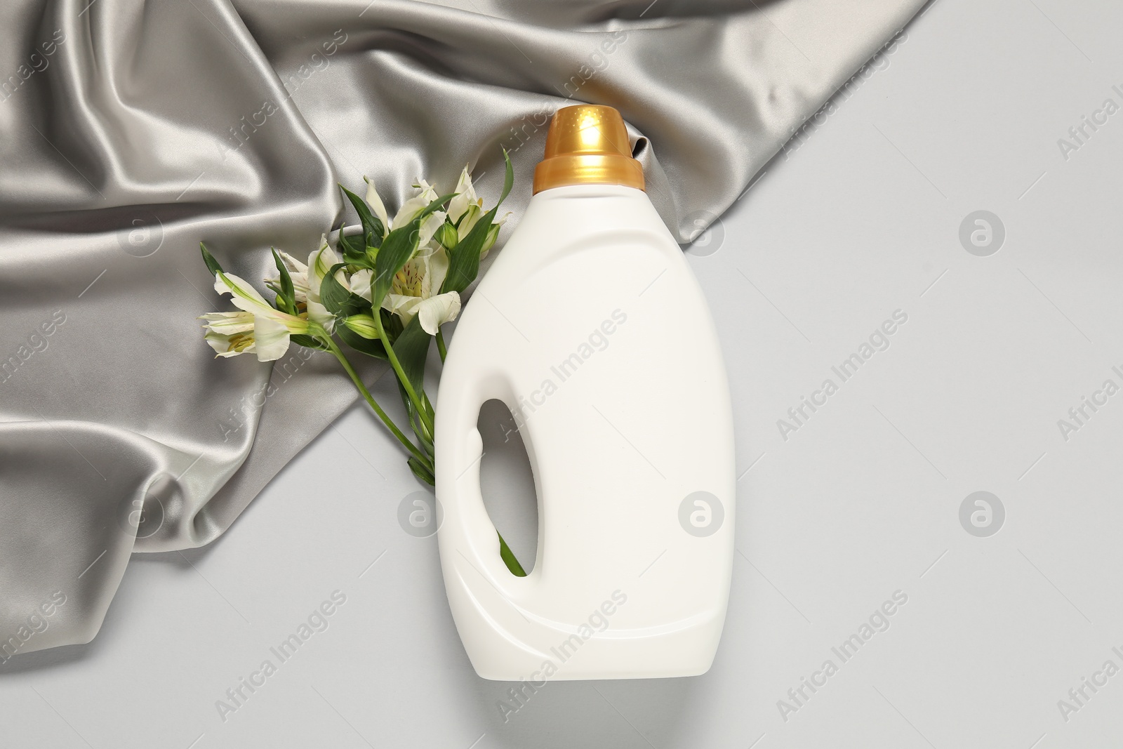 Bottle of fabric softener, flowers and color cloth on light grey background, flat lay Photo of Bottle of fabric softener, flowers and color cloth on light grey background, flat lay