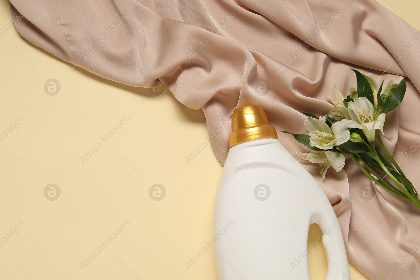 Bottle of fabric softener, flowers and color cloth on beige background, flat lay. Space for text Photo of Bottle of fabric softener, flowers and color cloth on beige background, flat lay. Space for text