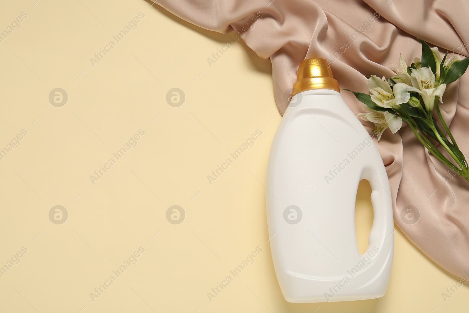 Bottle of fabric softener, flowers and color cloth on beige background, flat lay. Space for text Photo of Bottle of fabric softener, flowers and color cloth on beige background, flat lay. Space for text