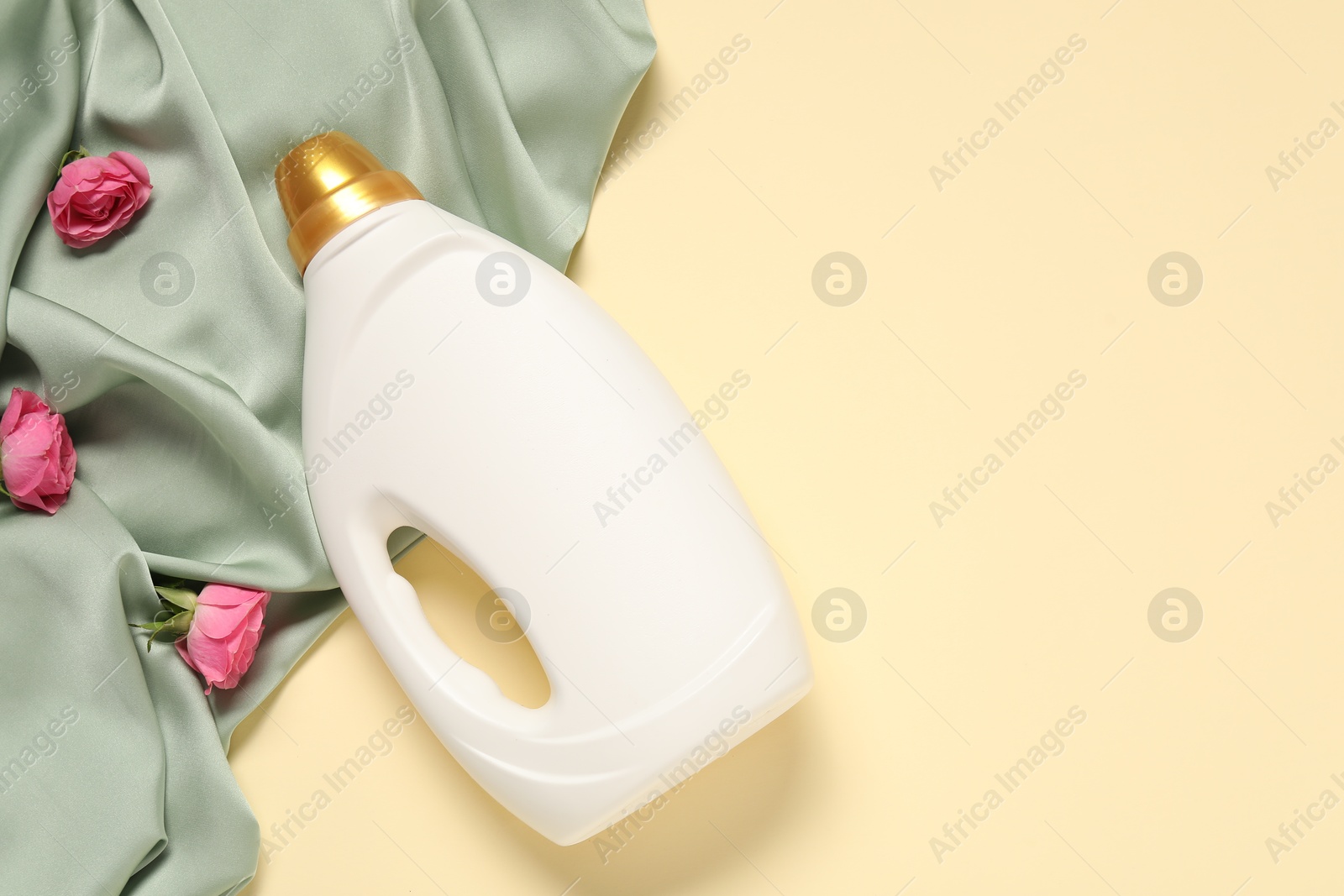 Bottle of fabric softener, flowers and green cloth on beige background, flat lay. Space for text Photo of Bottle of fabric softener, flowers and green cloth on beige background, flat lay. Space for text