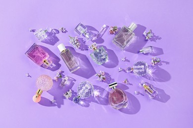 Photo of Flat lay composition with perfume bottles and lilac flowers on violet background