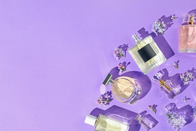 Photo of Flat lay composition with perfume bottles and lilac flowers on violet background. Space for text