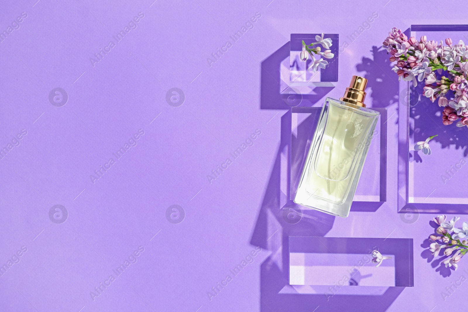 Flat lay composition with bottle of perfume and lilac flowers on violet background. Space for text Photo of Flat lay composition with bottle of perfume and lilac flowers on violet background. Space for text