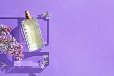 Photo of Flat lay composition with bottle of perfume and lilac flowers on violet background. Space for text