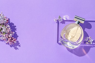 Photo of Flat lay composition with bottle of perfume and lilac flowers on violet background. Space for text