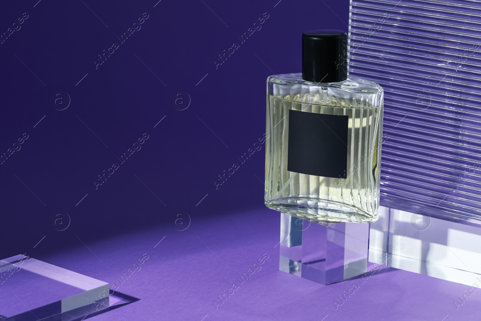 Stylish presentation of perfume bottle on purple background, closeup. Space for text Photo of Stylish presentation of perfume bottle on purple background, closeup. Space for text