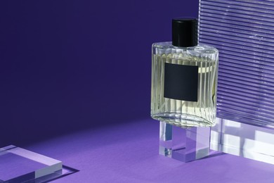 Photo of Stylish presentation of perfume bottle on purple background, closeup. Space for text