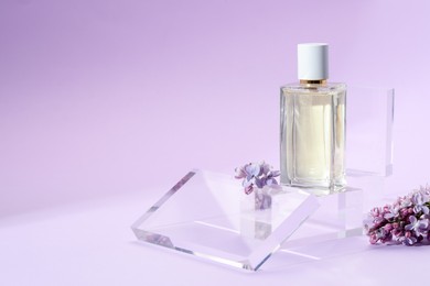 Photo of Stylish presentation of perfume bottle and lilac flowers on violet gradient background, closeup. Space for text
