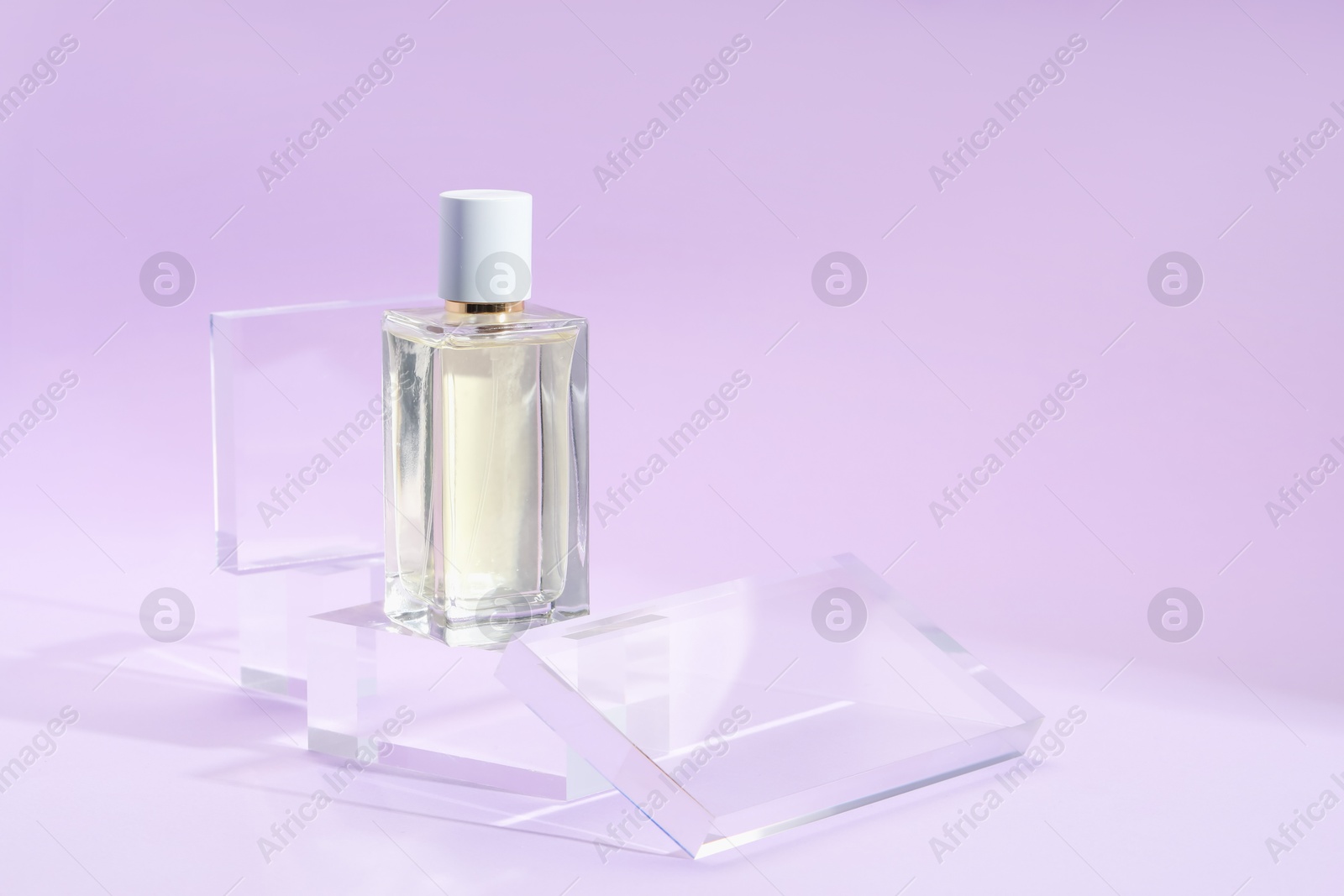 Stylish presentation of perfume bottle on violet background, closeup Photo of Stylish presentation of perfume bottle on violet background, closeup