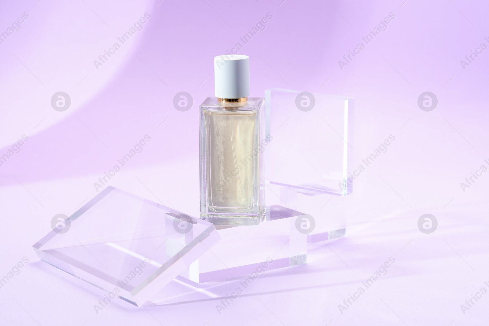 Stylish presentation of perfume bottle on violet background, closeup Photo of Stylish presentation of perfume bottle on violet background, closeup
