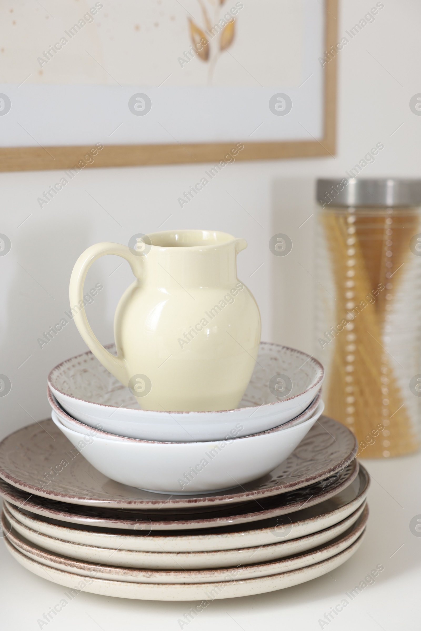 Clean ceramic jug, bowls and plates on white table in kitchen Photo of Clean ceramic jug, bowls and plates on white table in kitchen