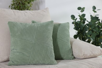 Photo of Two light green cushions on sofa indoors