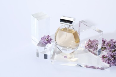 Photo of Stylish presentation of perfume bottle and lilac flowers on light grey background. Space for text