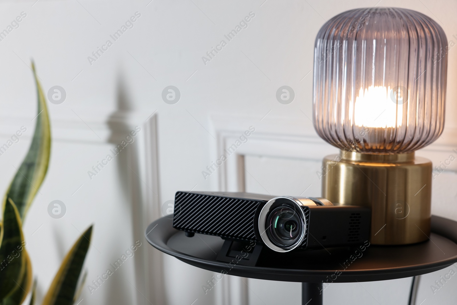 Modern video projector and lamp on black table, space for text Photo of Modern video projector and lamp on black table, space for text