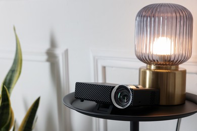 Photo of Modern video projector and lamp on black table, space for text