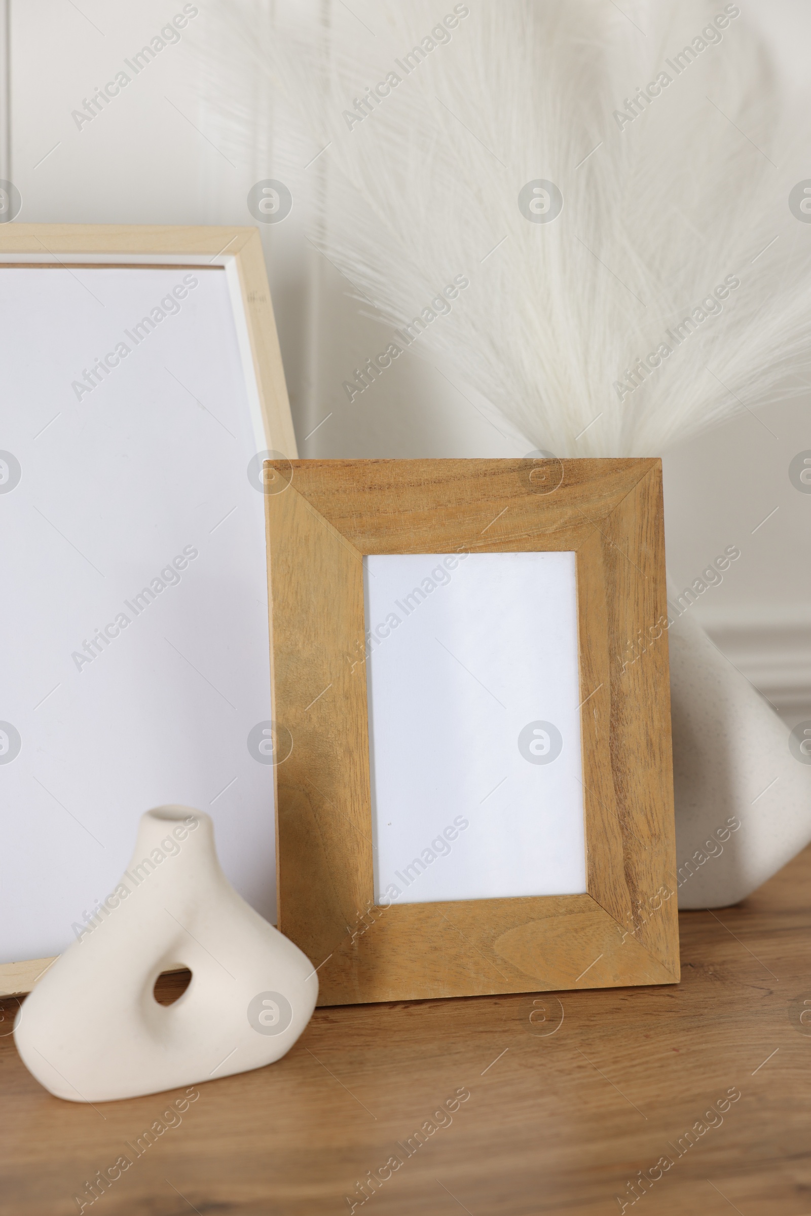 Empty photo frames and decor on wooden table near white wall Photo of Empty photo frames and decor on wooden table near white wall