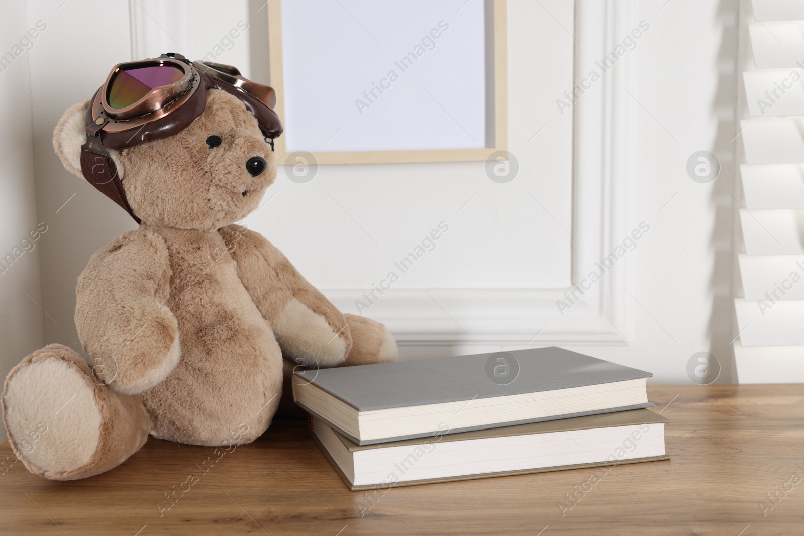 Teddy bear with vintage metal protective glasses and books on wooden table, space for text Photo of Teddy bear with vintage metal protective glasses and books on wooden table, space for text