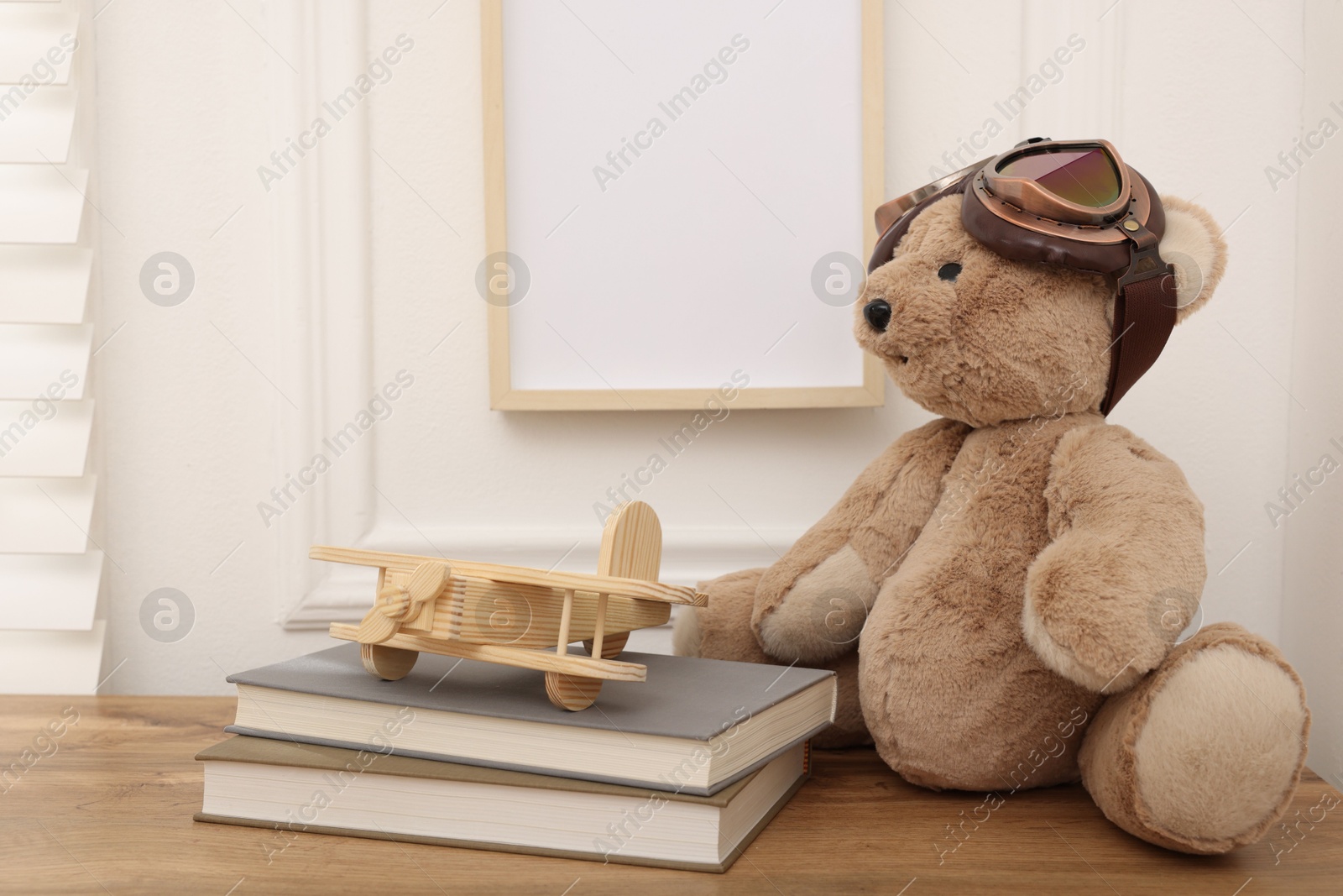 Teddy bear with vintage metal protective glasses, books and plane toy on wooden table Photo of Teddy bear with vintage metal protective glasses, books and plane toy on wooden table