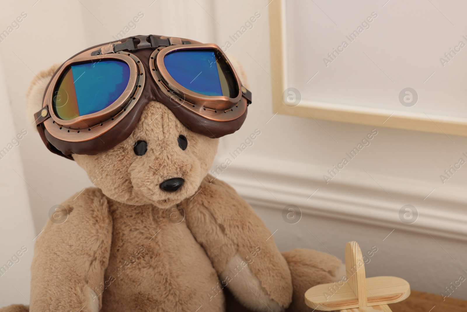 Teddy bear with vintage metal protective glasses and plane toy on wooden table, closeup Photo of Teddy bear with vintage metal protective glasses and plane toy on wooden table, closeup
