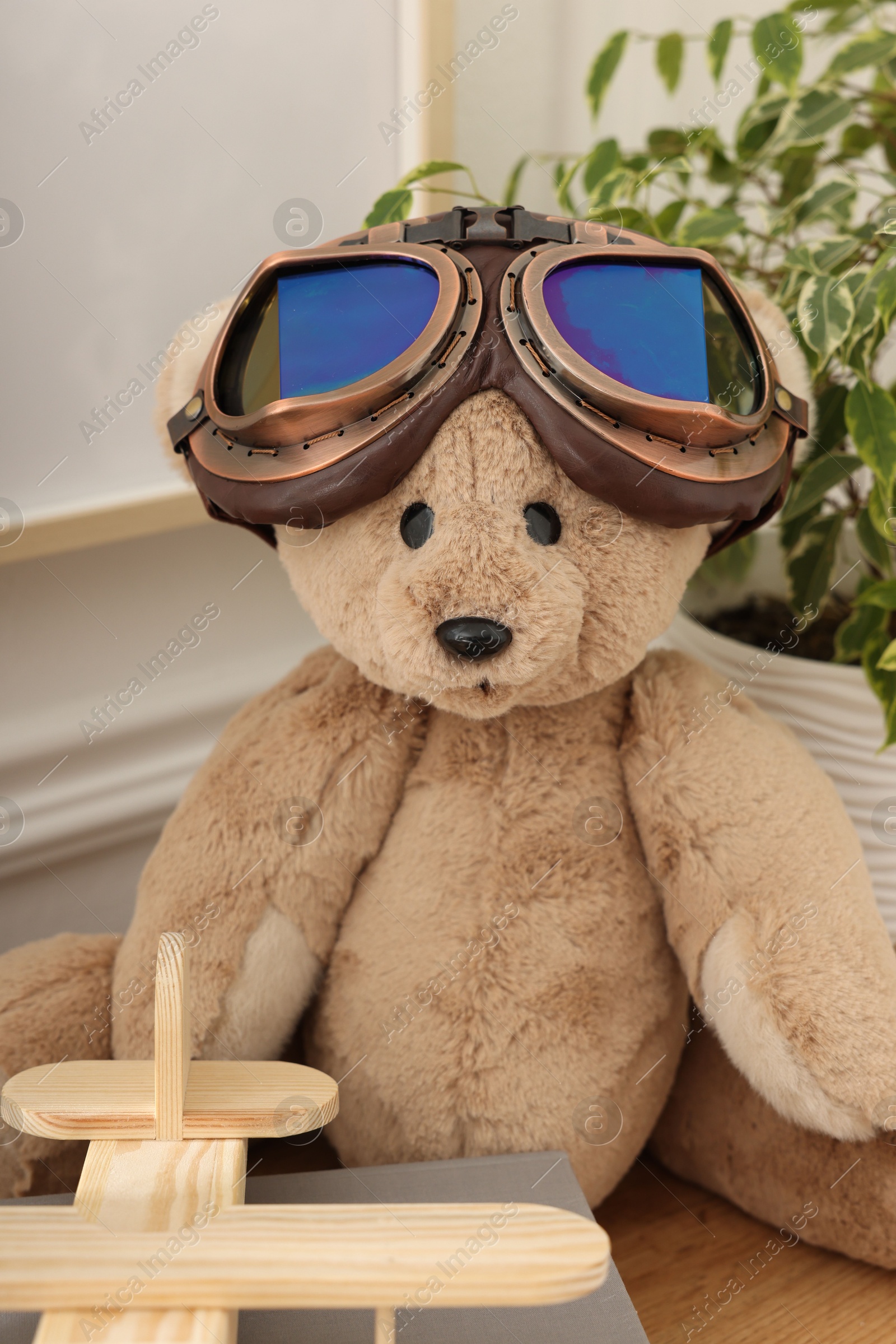 Teddy bear with vintage metal protective glasses, books and plane toy on wooden table Photo of Teddy bear with vintage metal protective glasses, books and plane toy on wooden table