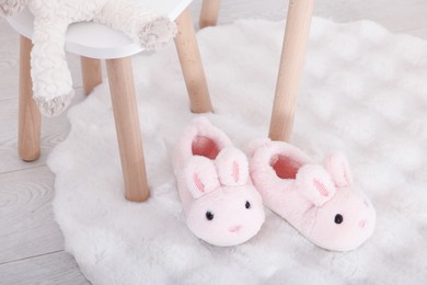 Photo of Cute kid slippers in shape of bunnies on floor indoors