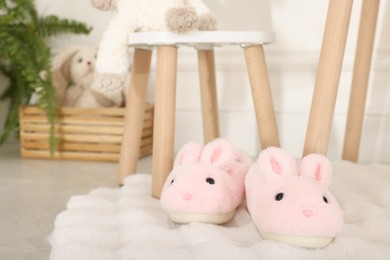 Photo of Cute kid slippers in shape of bunnies on floor indoors, space for text