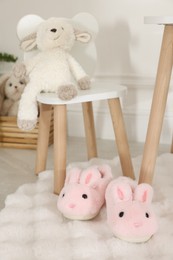 Photo of Cute kid slippers in shape of bunnies on floor indoors