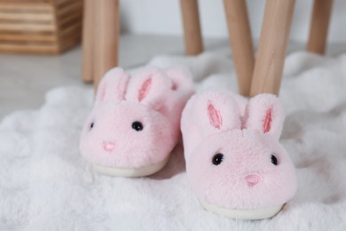Photo of Cute kid slippers in shape of bunnies on floor indoors