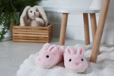 Photo of Cute kid slippers in shape of bunnies on floor indoors